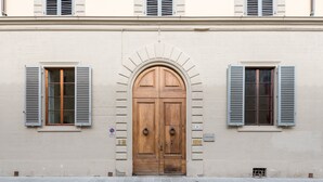 A building facade with a large wooden double door, two windows with shutters, and a small sign indicating the number 10.