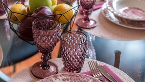 A dining table set with pink and white plates, a fruit bowl, and pink glassware.