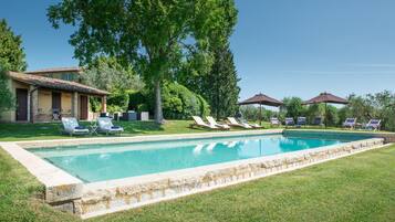 Relax by the serene pool surrounded by lush greenery and comfortable lounge chairs.