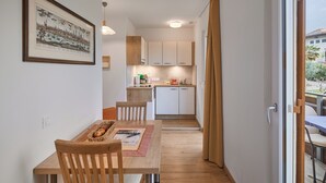 A compact kitchen with white cabinets, a dining area with a wooden table and chairs, and a framed picture on the wall. - Sunny apartment in an ideal location for active people, families, Genießer (Kaltern)