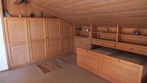 Ein Zimmer mit Holzboden, eingebauten Schränken, einer Bank und einem kleinen Regal mit Dekoration.