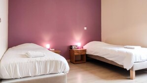 Una camera da letto con due letti, un comodino con una lampada e una luce a parete.