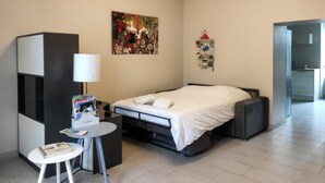Una camera d'albergo moderna con un letto, una scrivania, una sedia, una lampada e un quadro appeso al muro.