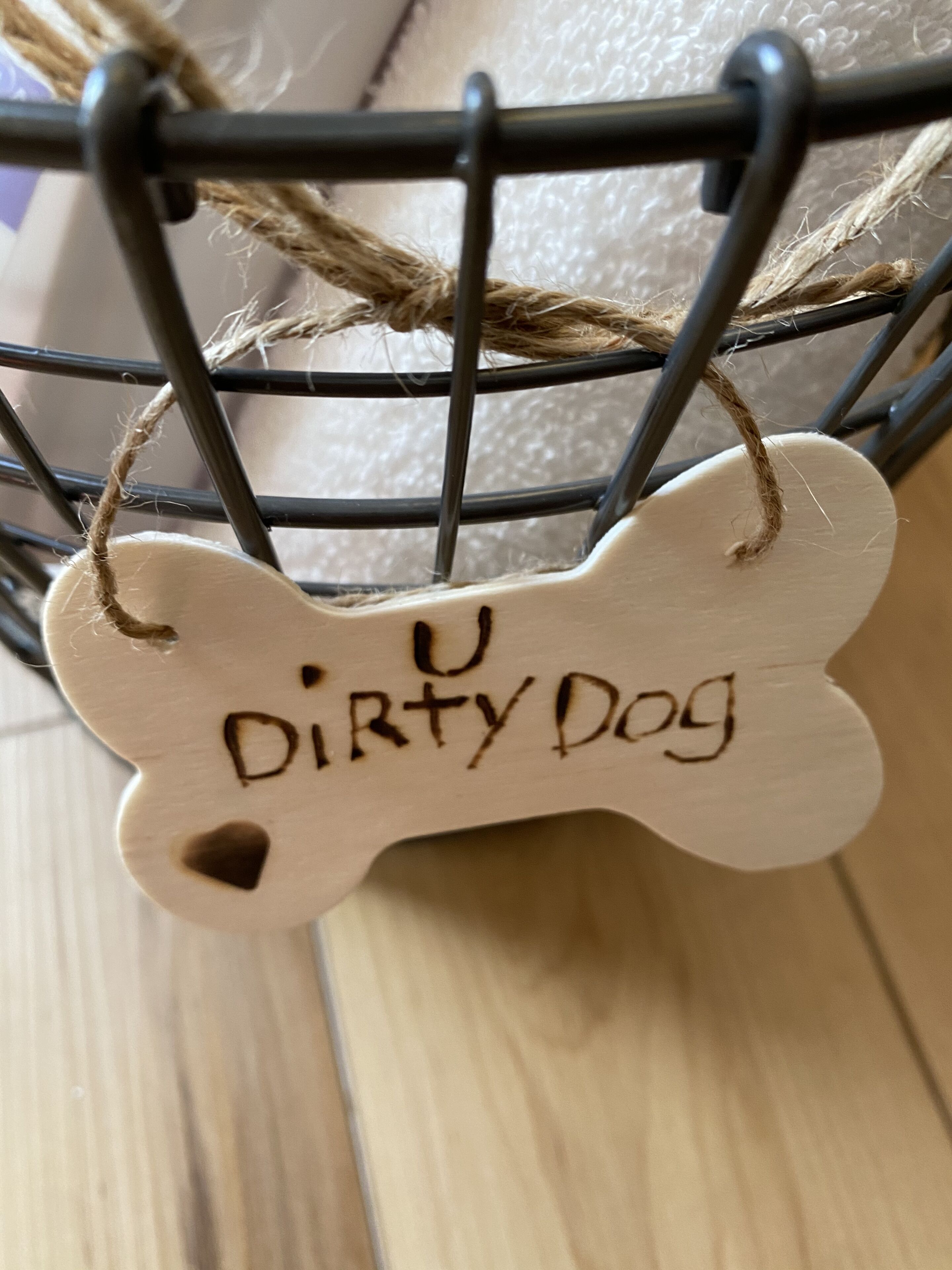 En træmærke i benform med teksten "Dirty Dog", hængende på en wire-konstruktion.
