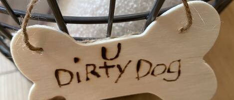 En træmærke i benform med teksten "Dirty Dog", hængende på en wire-konstruktion.