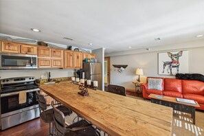 A modern kitchen with wooden cabinets, stainless steel appliances, and a wooden dining table. - Downtown Blowing Rock Getaway - STEPS to Shop & Dining - Cozy Fireplace "BEAR" (Blowing Rock)