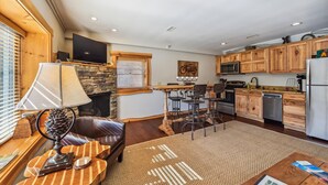 A spacious kitchen with wooden cabinets, a stone fireplace, and a dining area with a leather couch and a coffee table.