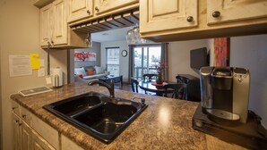 A kitchen with granite countertops, a built-in sink, a coffee maker, and wooden cabinets. - Stylish/Clean 1BD/BA Pointe Royale - Close to Pool - Great Guest Reviews (Branson)