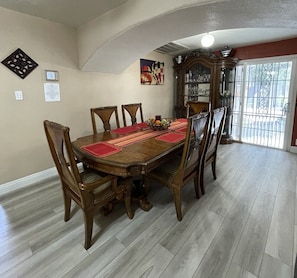 Un comedor con una gran mesa de madera, seis sillas y un aparador decorativo.