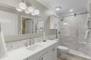 Une salle de bain moderne avec un grand miroir, un lavabo, des toilettes et un espace douche.