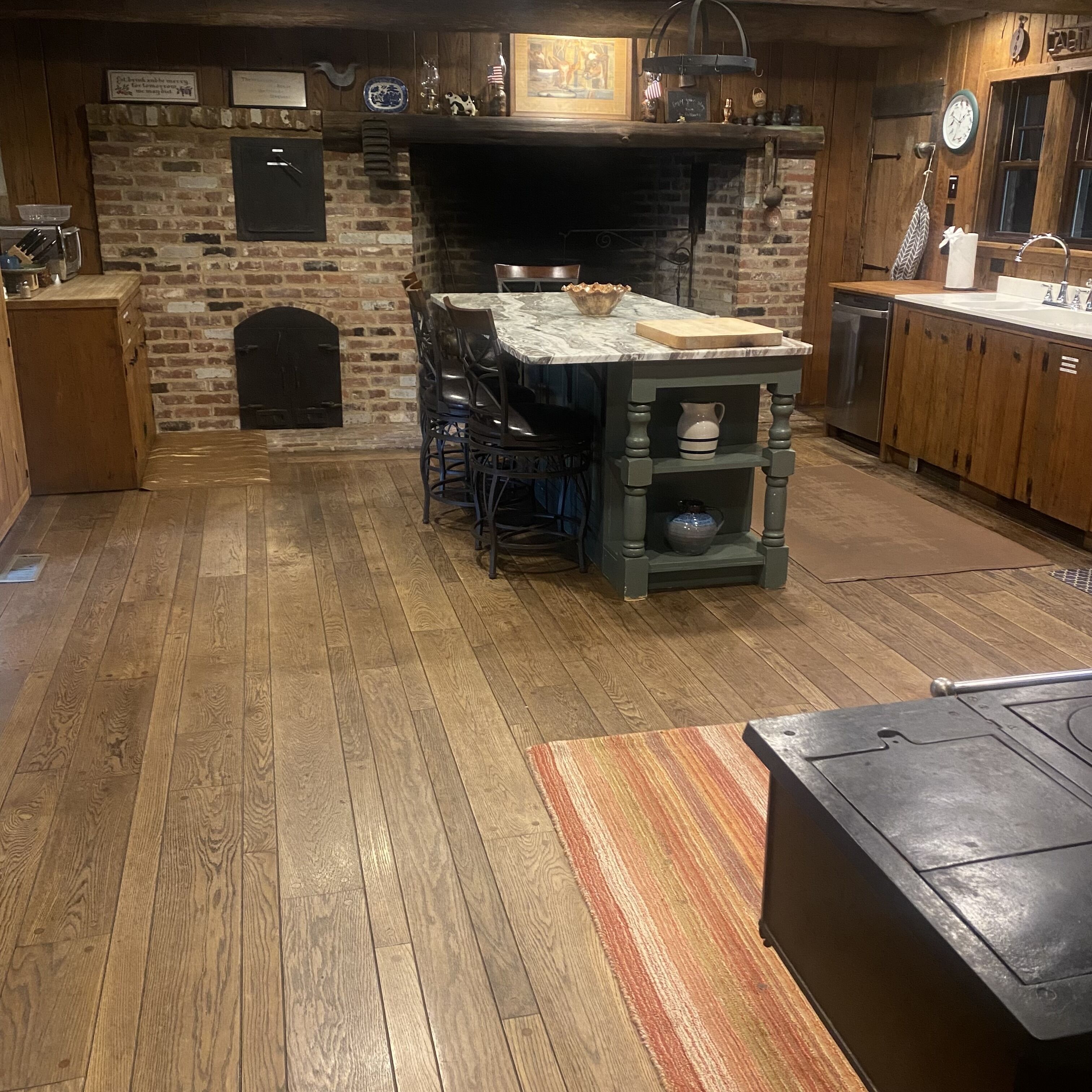 A kitchen with a brick fireplace, wooden cabinets, and a dining table.
