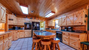 Eine geräumige Küche mit Holzausstattung, einer zentralen Kochinsel mit Hockern und einem eingebauten Backofen.