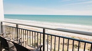 Ein Balkon mit Stühlen mit Blick auf einen Strand.