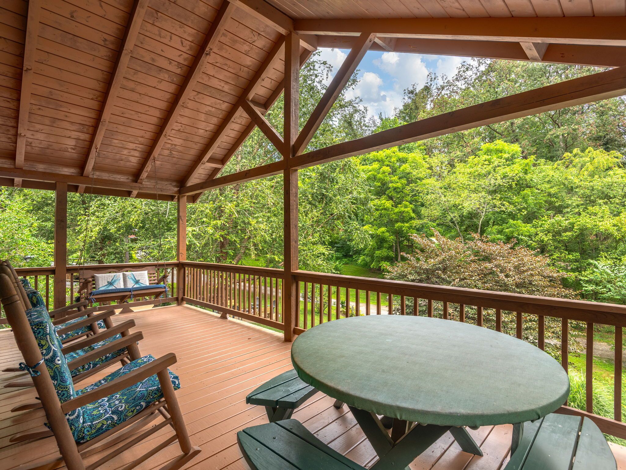 A wooden deck with a table and benches, overlooking a lush green forest.