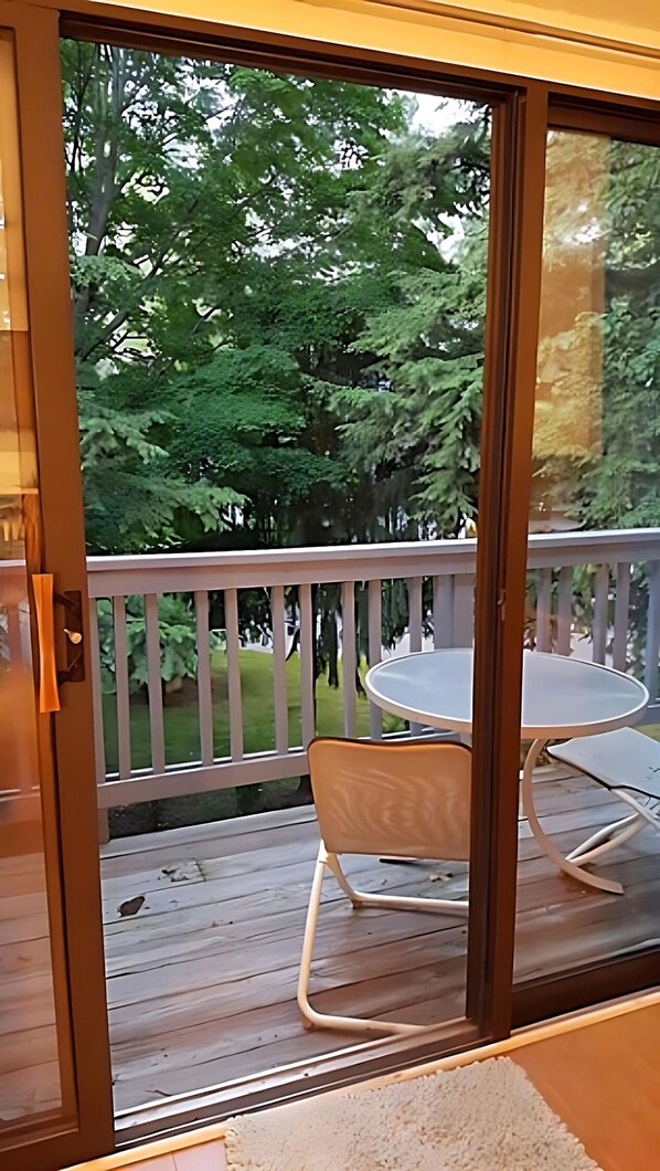 A deck with a glass door leading to a garden.