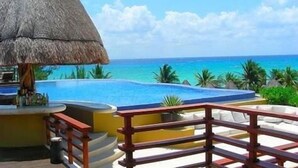 A poolside area with a thatched roof, a bar, and a view of the ocean. - Fab Condo - 14 Steps to Beach, with Panoramic Roof View (Playa del Carmen)