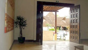 A hotel lobby with a large open door leading outside, a potted plant, and a wall-mounted sign. - Fab Condo - 14 Steps to Beach, with Panoramic Roof View (Playa del Carmen)