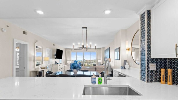 A modern kitchen with a central island, a dining area with a view, and a living space with a TV. - 4 Bedroom/ 3 Bath With Amazing Views, You can Have It All! Modern Condo designed for comfort and Sty (Miramar Beach)