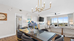 A modern hotel room with a dining area, a TV, a balcony with a view, and a ceiling fan. - 4 Bedroom/ 3 Bath With Amazing Views, You can Have It All! Modern Condo designed for comfort and Sty (Miramar Beach)