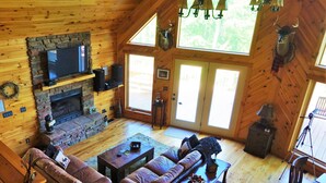 A cozy log cabin interior with a stone fireplace, leather sofas, and a television. - Near Wine Country & Parks. Great Hiking & Amazing Views! Reduced June rates! (Hays)