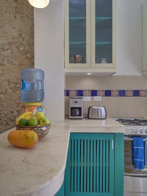 A kitchen with a water dispenser, a bowl of fruit, a stove, and a toaster.