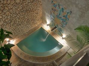 Une piscine circulaire avec un mur en pierre et un mur décoré de mosaïques.