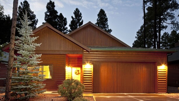 A two-story log cabin with a garage, surrounded by trees and a gravel driveway. -  Pinetop Lakes CClub, One Level, AC, Private, Gated, Close To Amenities! (Pinetop)