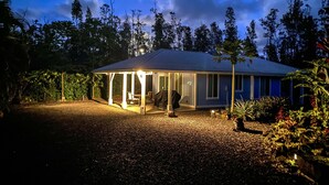 Ein Haus mit überdachter Terrasse, Grillplatz und gepflasterter Auffahrt.