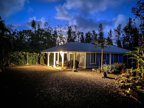 Surrounded by lush vegetation, this single-story house offers a serene outdoor space with a covered patio and comfortable seating.