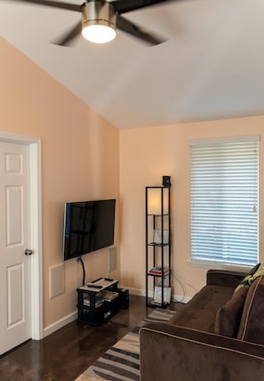Relax in a stylish living room with a ceiling fan, flat-screen TV, and comfortable sofa.