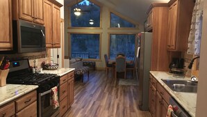 Una cocina con armarios de madera, una estufa y un refrigerador. Hay un comedor con una mesa y sillas.