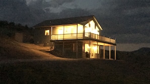 Una casa de dos pisos con balcón, ubicada en una ladera.