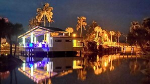 A waterfront property with a covered area, palm trees, and a reflection in the water. - E25 Direct Gulf Front is open!  Beautiful and new!  Saturday-Saturday (Sanibel)