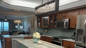 A modern kitchen with a marble island, stainless steel appliances, and wooden cabinets. - E25 Direct Gulf Front is open!  Beautiful and new!  Saturday-Saturday (Sanibel)