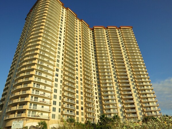 A high-rise residential building with multiple balconies and a clear sky.
