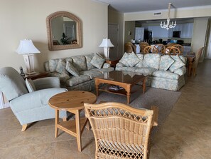 A living room with a sofa, two armchairs, a coffee table, and a dining area with chairs and a table.
