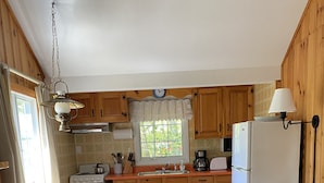 Una cocina acogedora con armarios de madera, una mesa de comedor con sillas, un refrigerador y una cafetera.