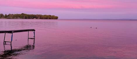 Un lago tranquilo al atardecer con un muelle de madera que se adentra en el agua.