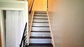 A staircase with wooden steps and a white handrail, leading to a door at the top. - Experience the charm of a rustic lakefront cottage, perfect for year-round fun! (Constantia)