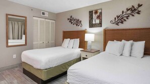 A hotel room with two beds, a window with curtains, a wardrobe, and decorative wall art.