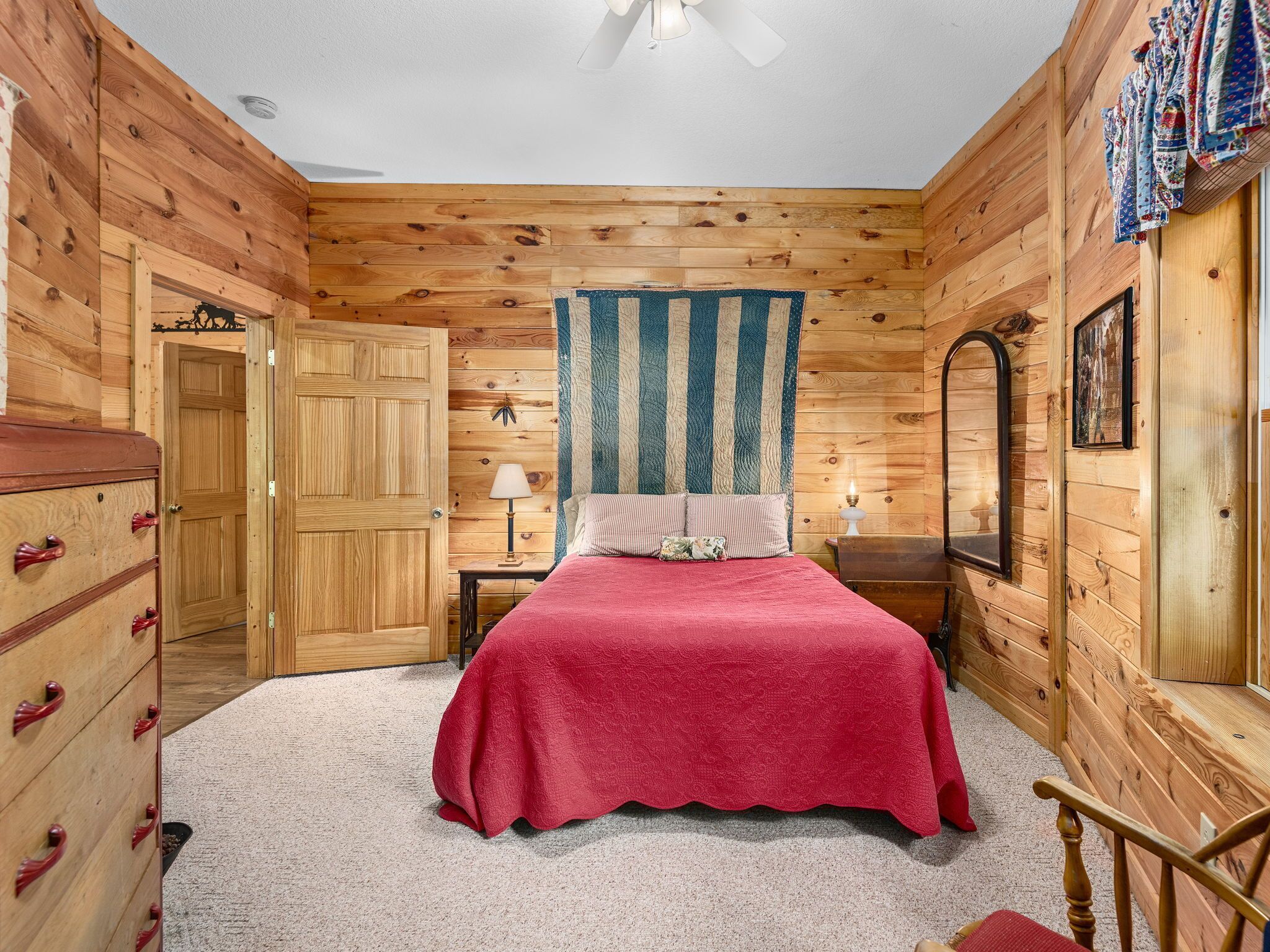 A wooden-paneled bedroom with a bed, dresser, and a mirror.
