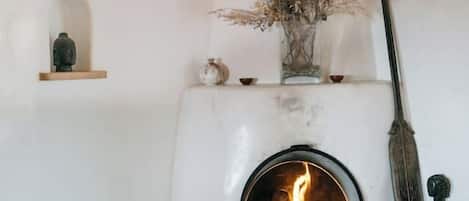 Una habitación acogedora con chimenea, una estantería con adornos y una mesa con libros.