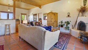 A cozy living room with a sofa, a fireplace, and a tiled floor. - Stella Luna in Arroyo Seco - Hot Tub - Longterm (Taos)