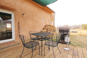 Un patio al aire libre con una mesa y sillas, una parrilla y una pila de leña.