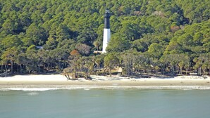 Un faro rodeado de un bosque tupido y una playa arenosa.