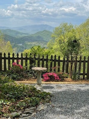 A garden with a stone birdbath, a wooden fence, and a view of distant hills. - Retreat in the Sky....For All Those Special Occasions!.... (Bryson City)