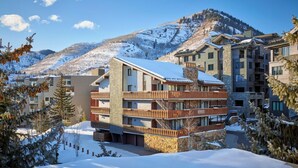 A multi-story hotel with a stone facade, wooden balconies, and a view of a snowy mountain. - Enzian 315 - 4 Bedroom Diamond (Vail)