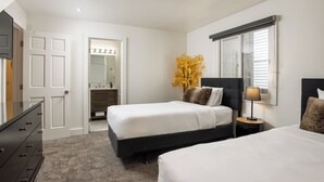 A bedroom with two beds, a dresser, a vanity with a mirror, and a window with blinds. - Enzian 315 - 4 Bedroom Diamond (Vail)
