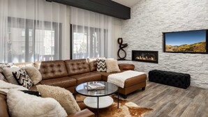 A modern living room with a leather sectional sofa, a glass coffee table, and a fireplace. - Enzian 315 - 4 Bedroom Diamond (Vail)