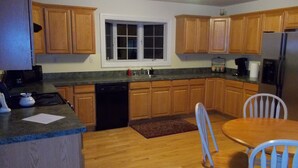 A kitchen with wooden cabinets, a dishwasher, a refrigerator, and a dining table with chairs.